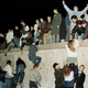 East German citizens climb the Berlin wall at the Brandenburg Gate as they celebrate the opening of the East German border in this November 10, 1989 file photo.